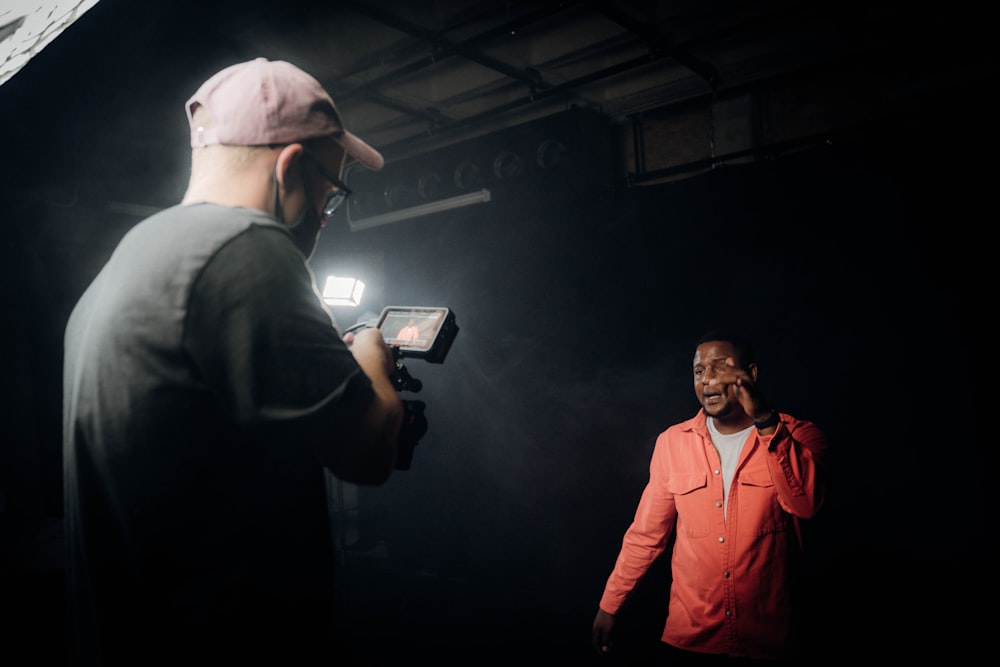 man in orange jacket standing beside man in black suit