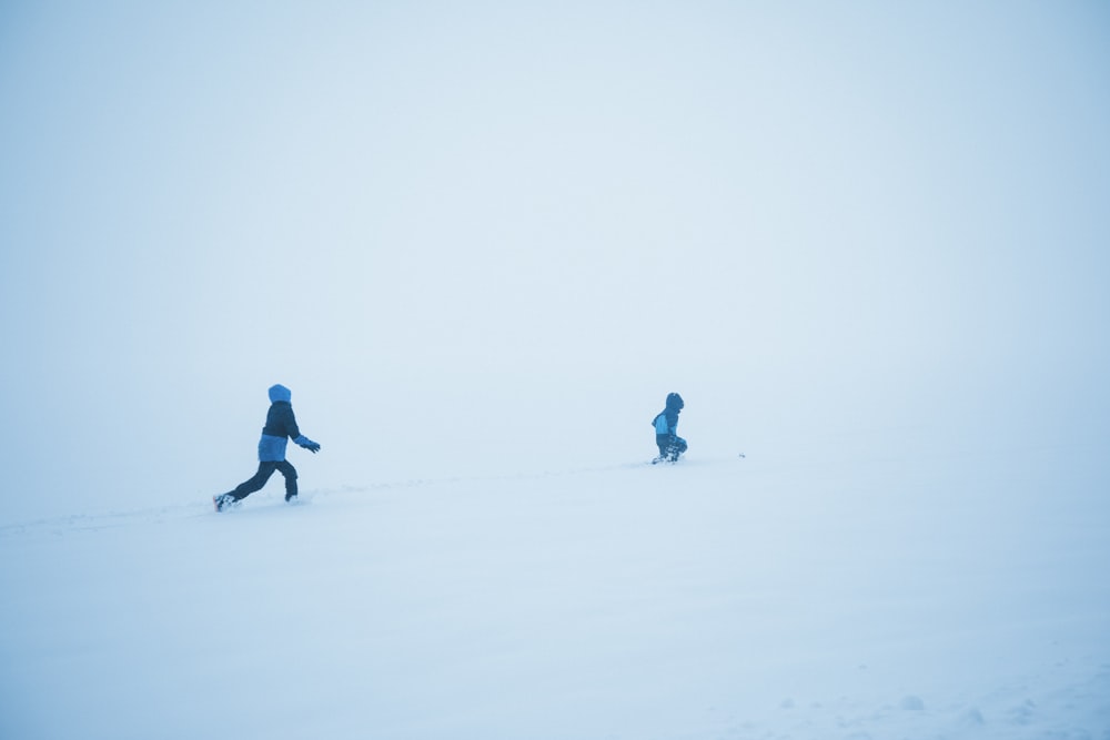 person in blue jacket and black pants walking on snow covered ground during daytime