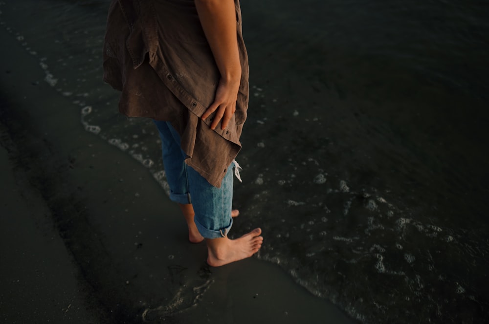 person in blue denim jeans standing on beach
