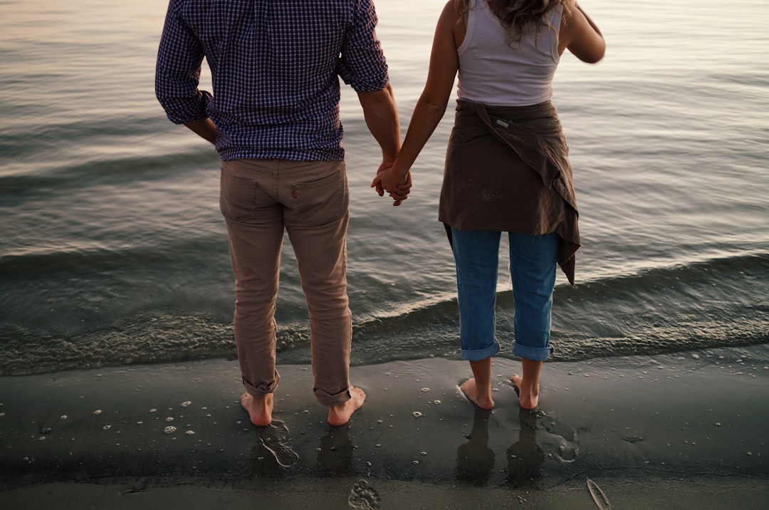 man and woman standing on beach during daytime