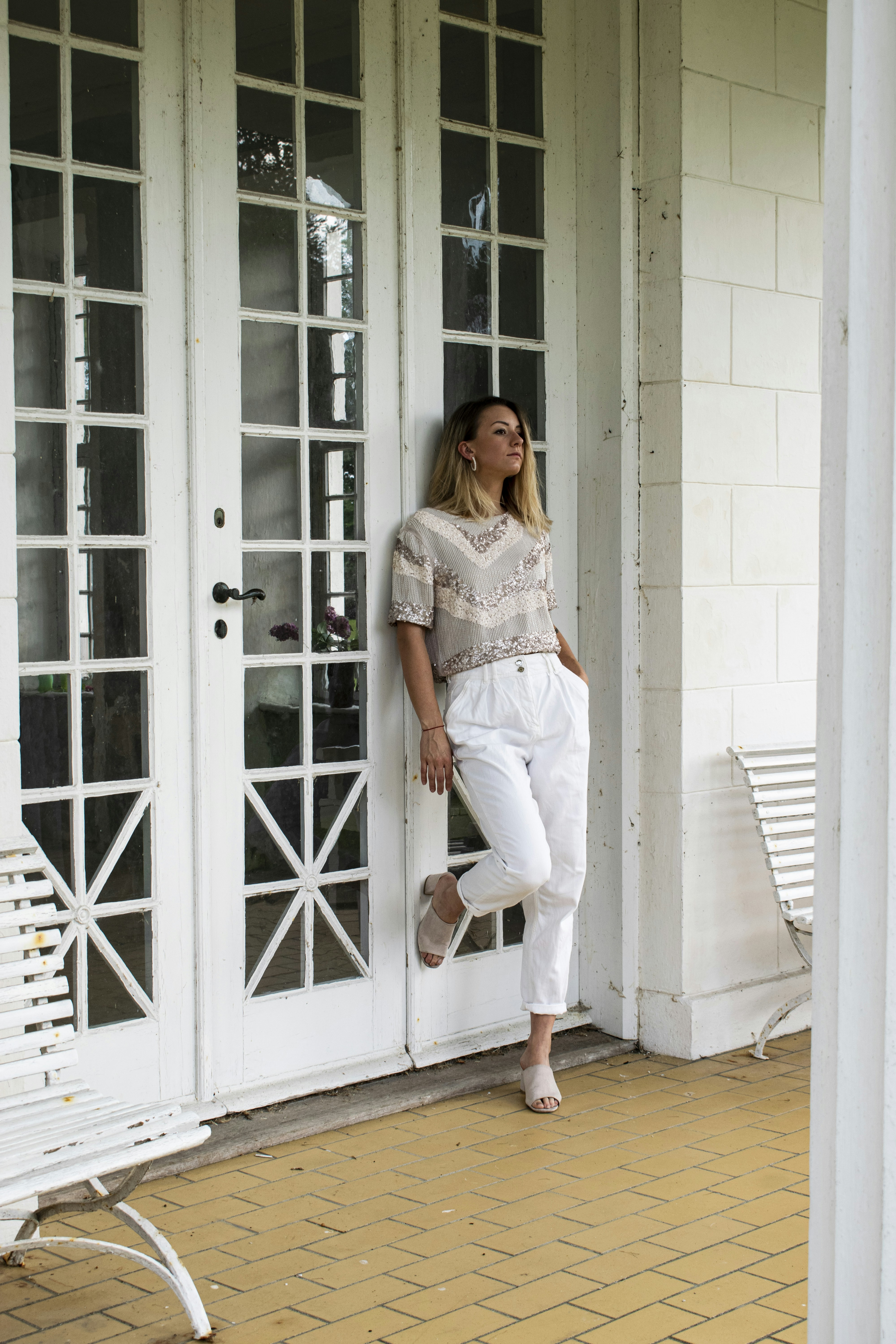 woman in white dress and white pants standing beside white wooden door
