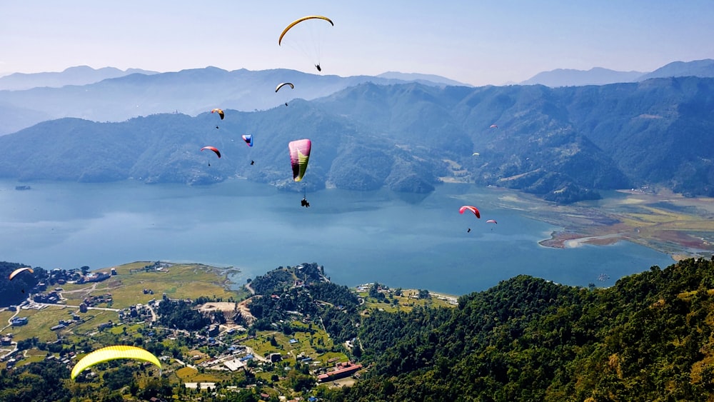 people on parachute over green mountains during daytime