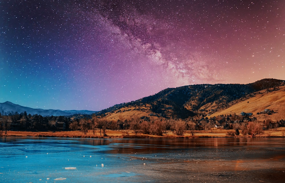 brown mountain beside body of water during night time