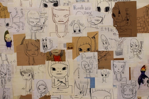 A collage of various doodles and sketches, primarily depicting cartoonish characters with large eyes. Some characters are holding musical instruments like guitars. Handwritten text appears throughout, with phrases such as 'This machine kills fascists' and 'Punch me hard.' The doodles are on different pieces of paper, some colored and some plain, layered over each other.