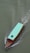 A wooden boat with a turquoise canopy is moving through greenish water, leaving a trail of ripples behind. There is a black tire attached to the top of the canopy.