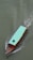 A wooden boat with a turquoise canopy is moving through greenish water, leaving a trail of ripples behind. There is a black tire attached to the top of the canopy.