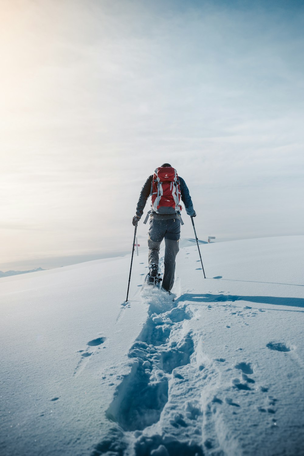 person in red jacket and black pants standing on snow covered ground during daytime