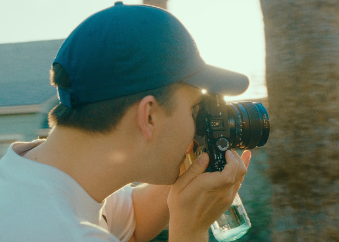 man in white shirt holding black dslr camera