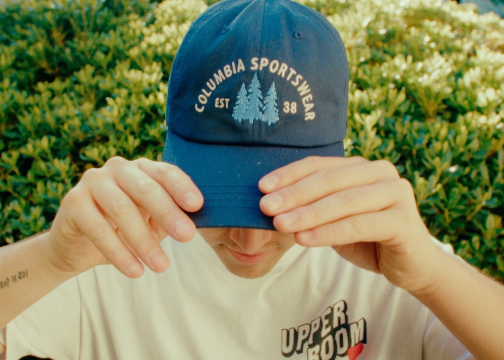 man in white and blue crew neck t-shirt wearing blue and white fitted cap