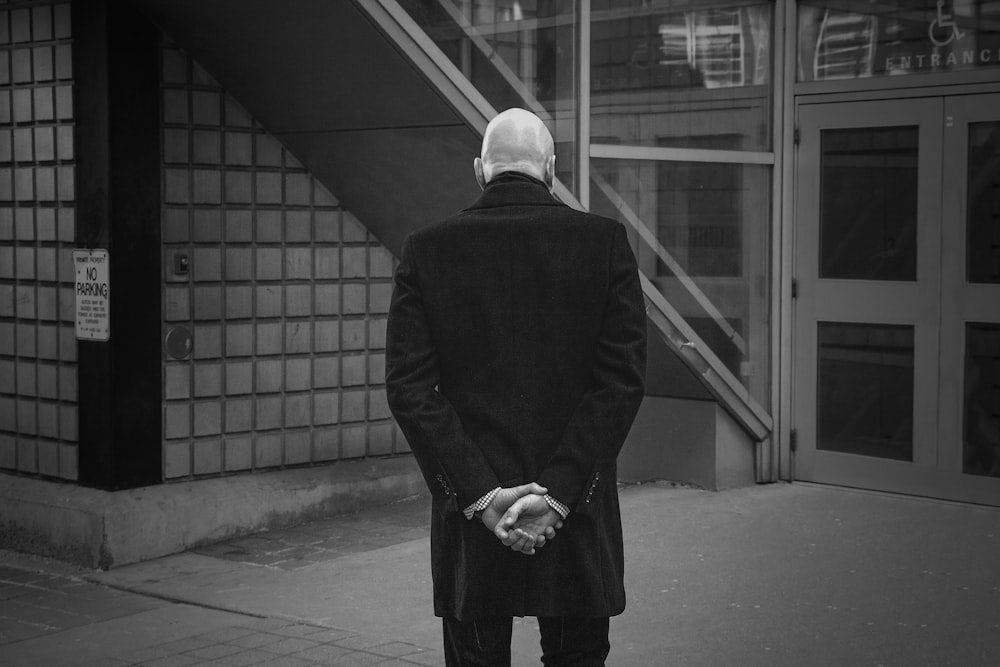 man in black suit standing on sidewalk