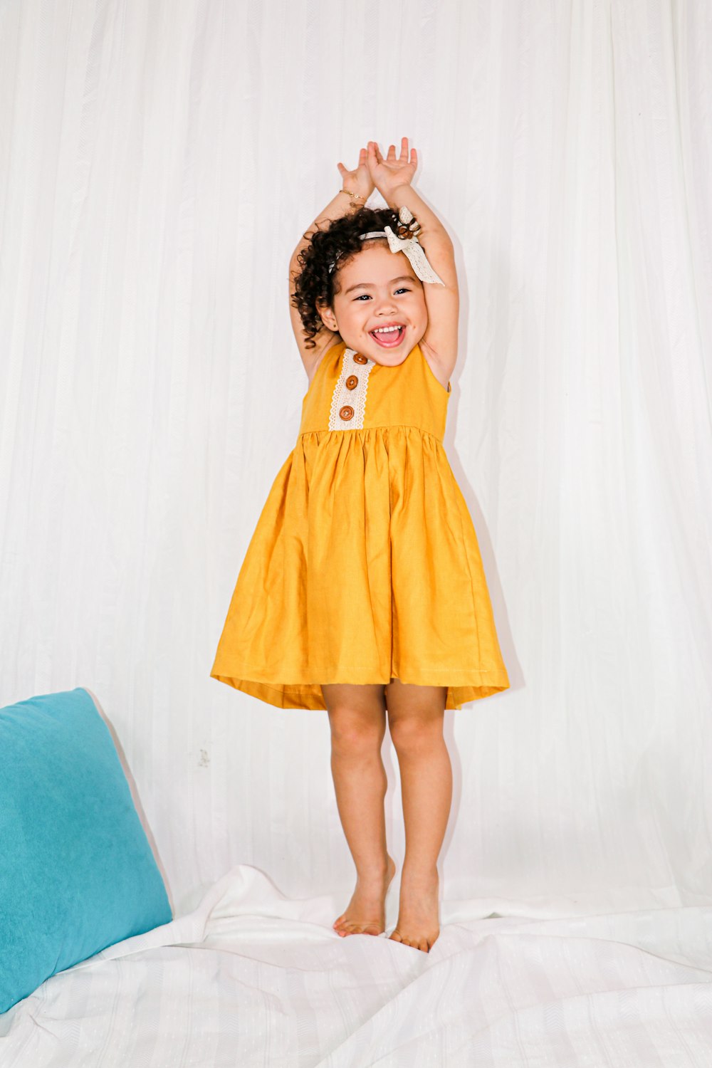 girl in yellow dress standing on blue chair