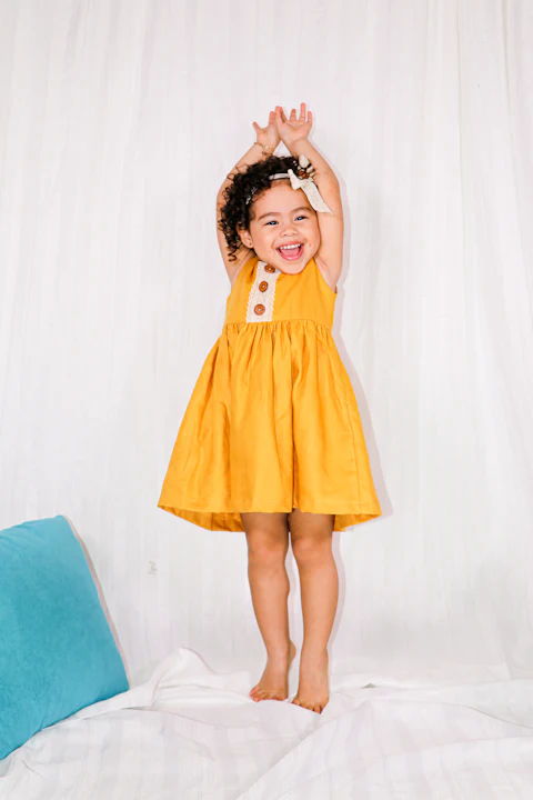 Menina de vestido amarelo sobre fundo claro