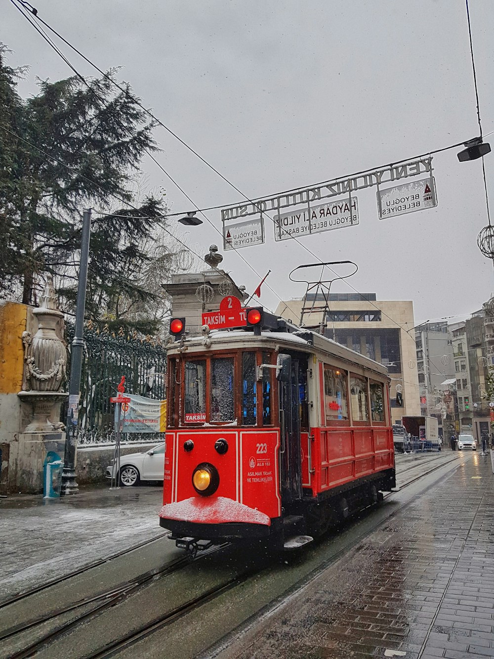 昼間、建物近くの道路を走る赤い路面電車