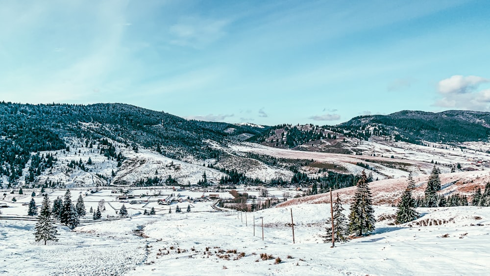 campo coberto de neve e montanhas sob o céu azul durante o dia