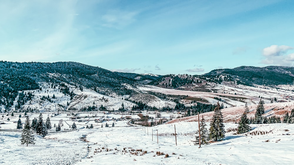 snow covered field and mountains under blue sky during daytime