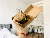 person holding burger with lettuce and cheese