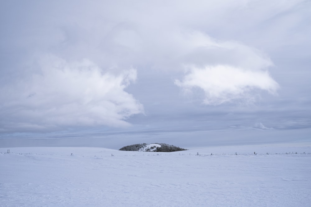 snow covered field under cloudy sky during daytime