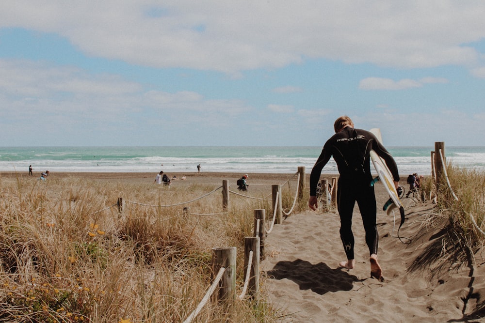 man in black jacket and black pants walking on beach during daytime