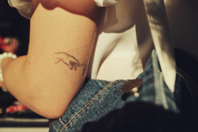 Tattooed forearm resting on denim