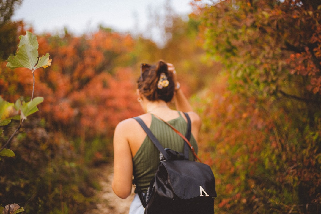 woman in black tank top and black backpack standing near green trees during daytime