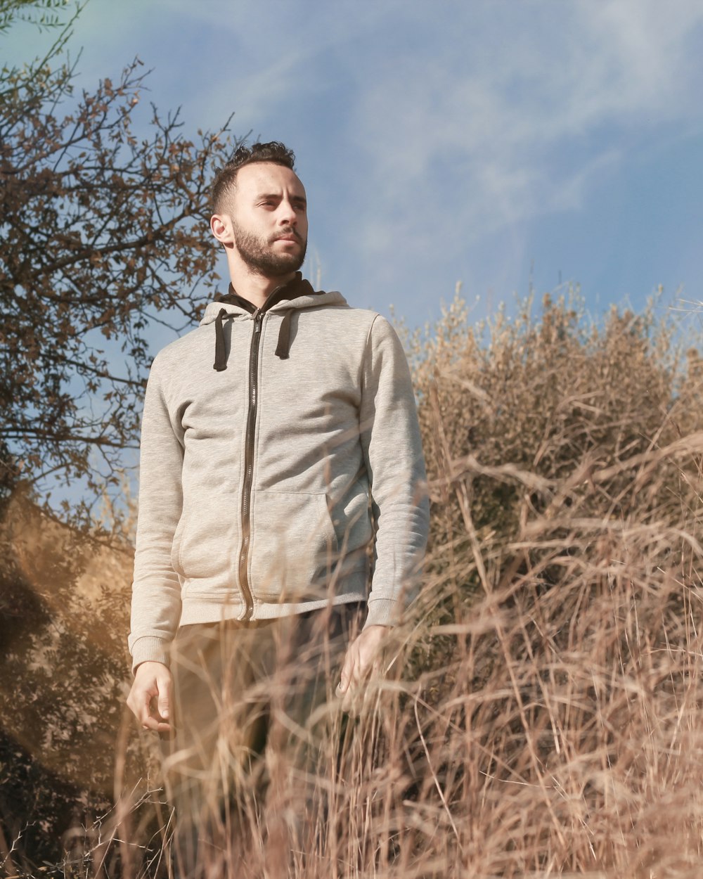 man in gray zip up jacket standing on brown grass field during daytime