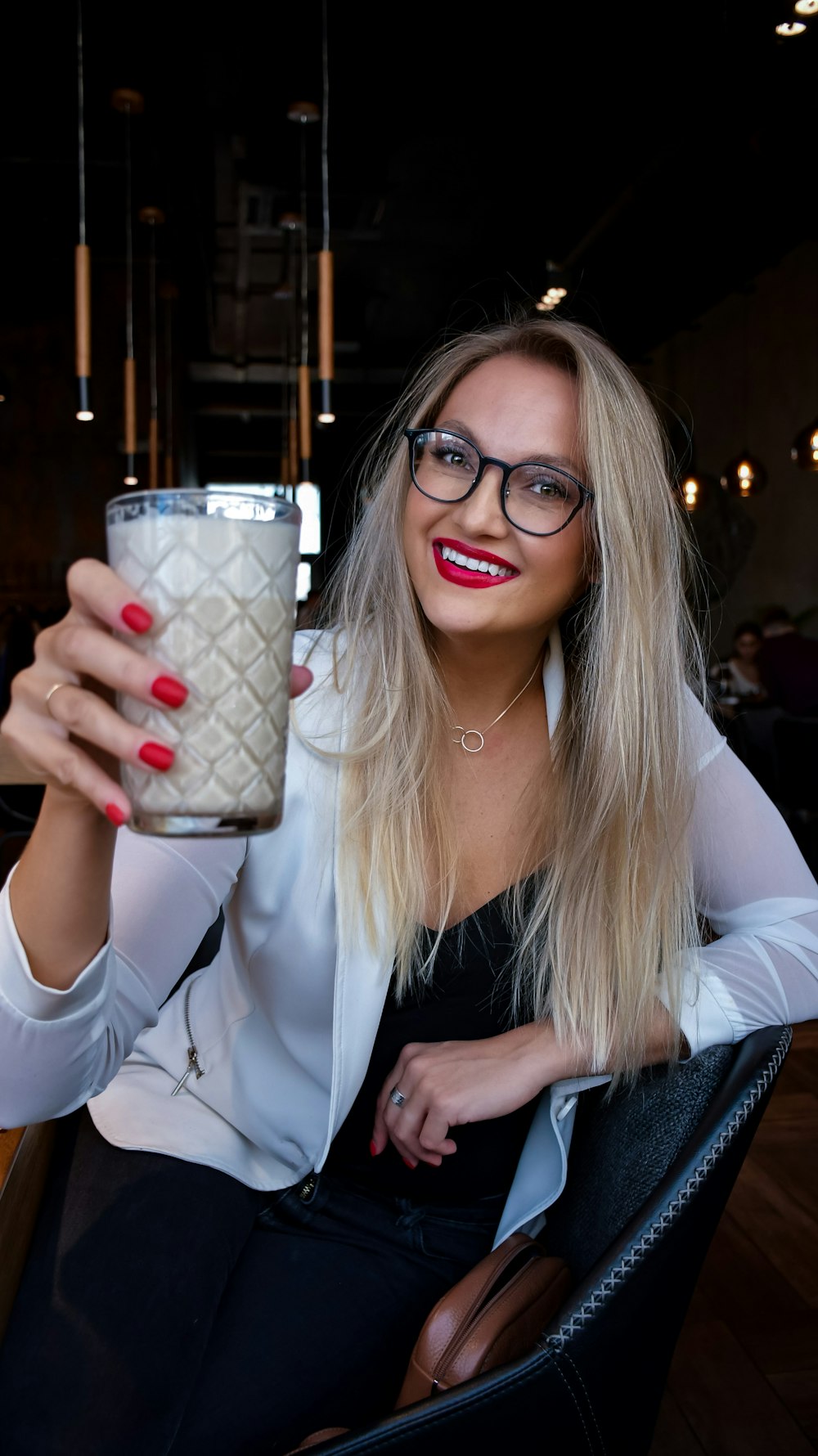 woman in white blazer holding white and red ceramic mug