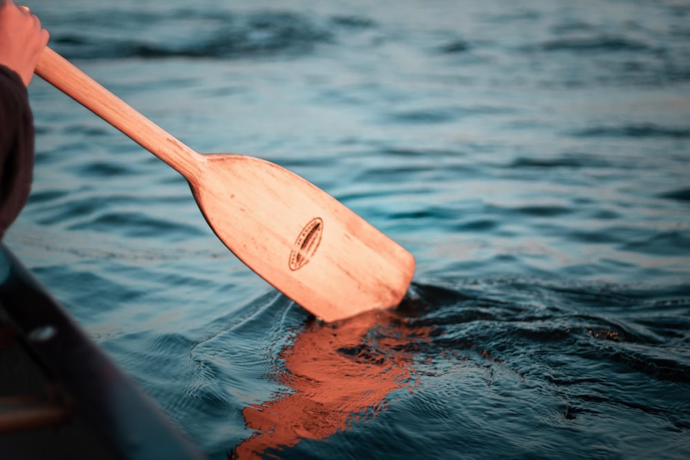 brown wooden paddle on body of water during daytime