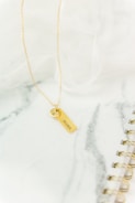 gold cross pendant necklace on white textile