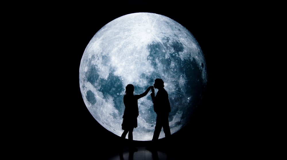 hombre y mujer de pie sobre una luna redonda