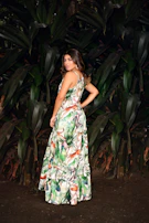 A model wearing a hand-dyed, eco-friendly dress standing against a backdrop of lush greenery.