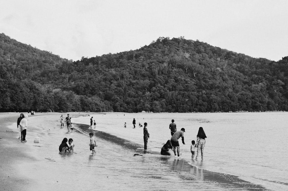 grayscale photo of people playing on beach