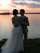 Couple posing elegantly by a serene lake during golden hour.