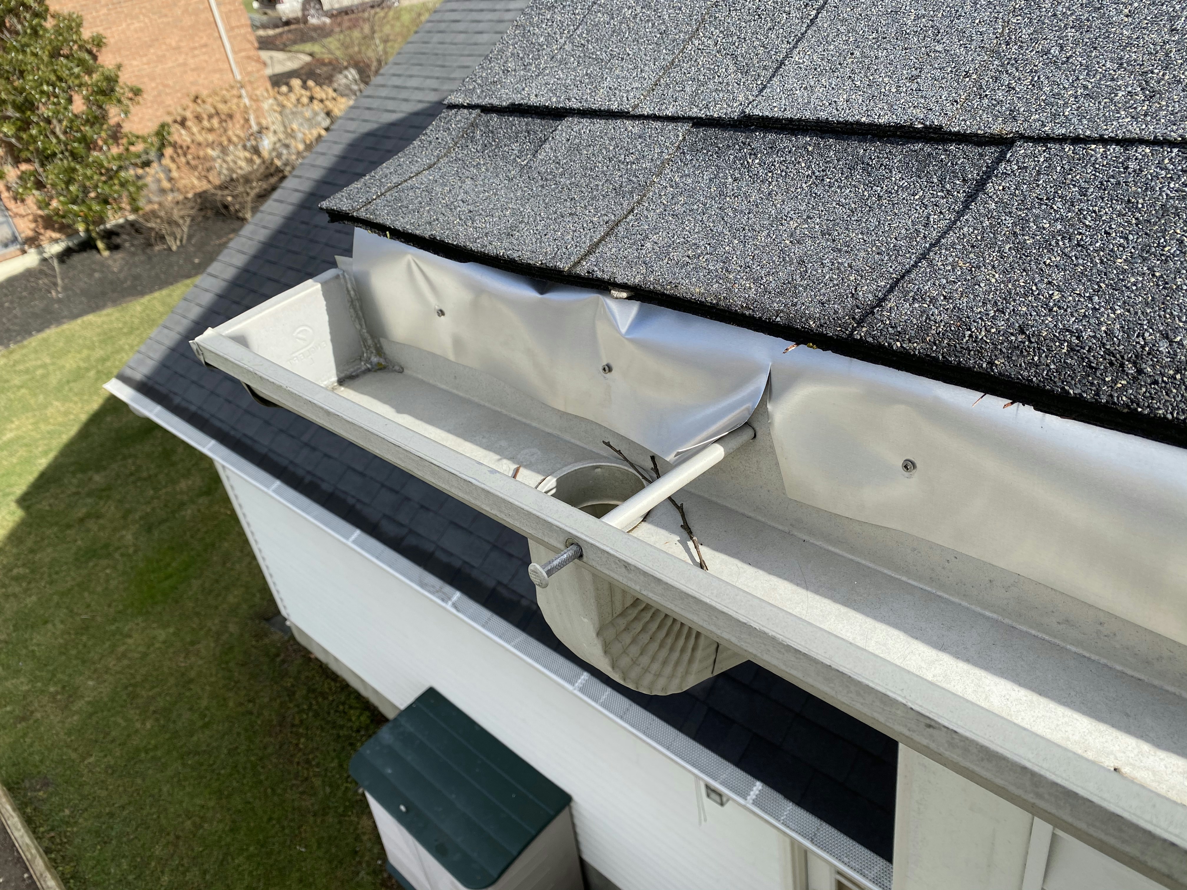 Aerial drone view of clean residential rooftop with clear gutters on a clear day, bright sky, well-maintained UK housing