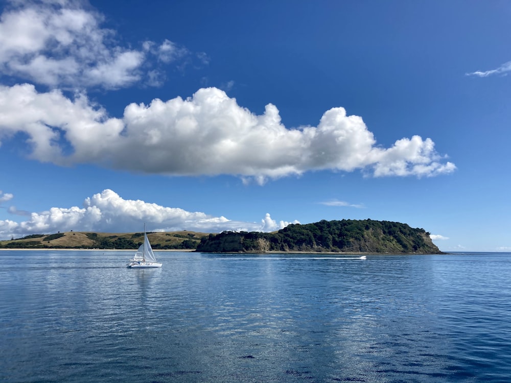 white sailboat on sea under blue sky and white clouds during daytime