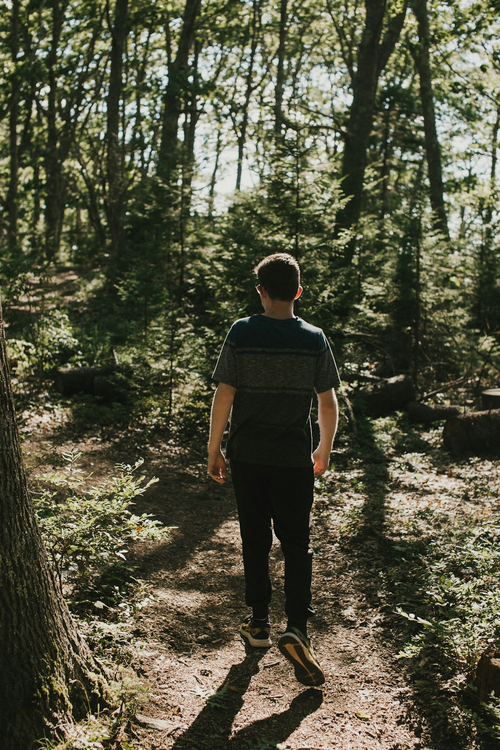 man in black t-shirt and black pants standing in forest during daytime