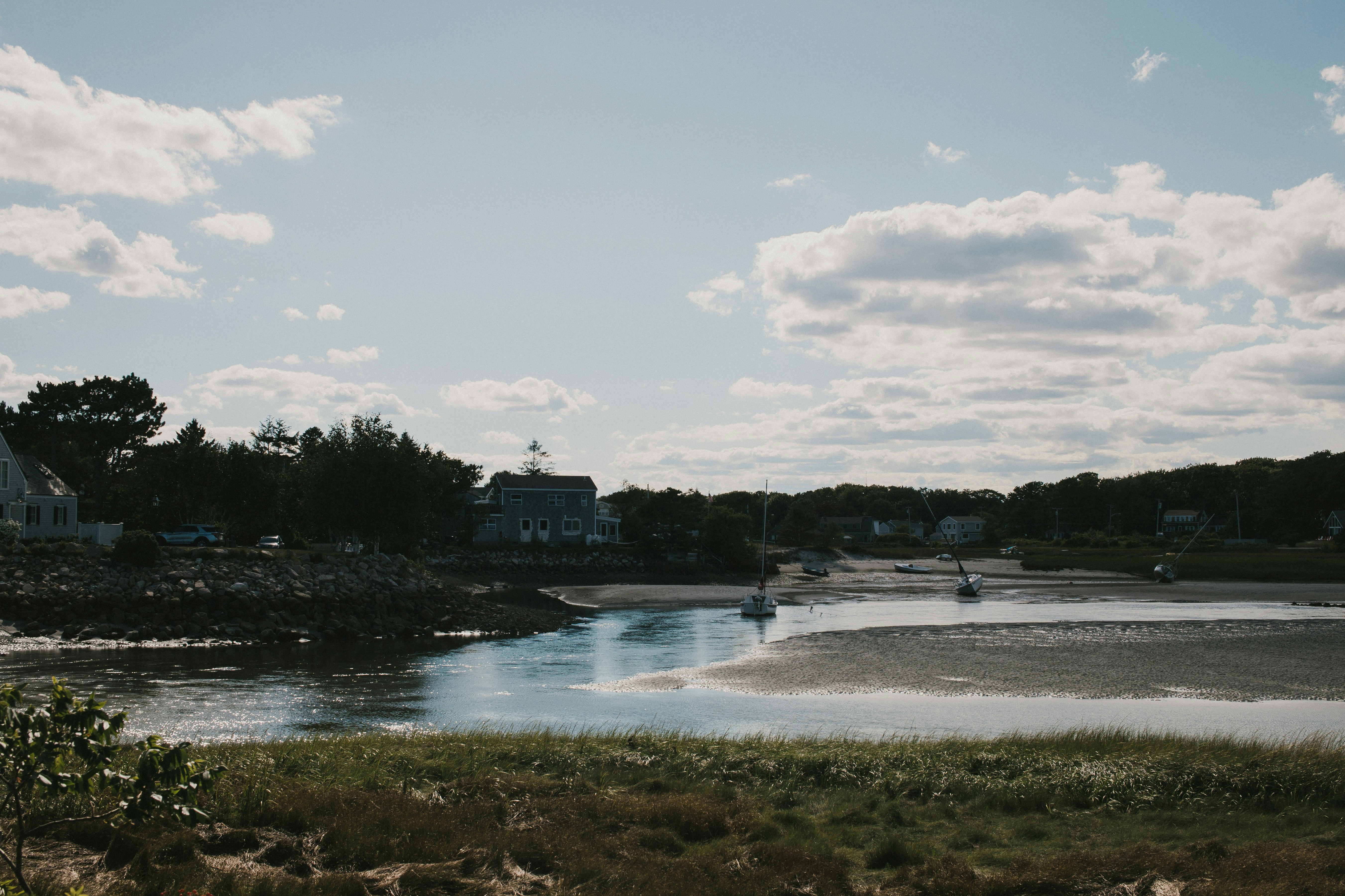 body of water near trees and buildings under white clouds and blue sky during daytime