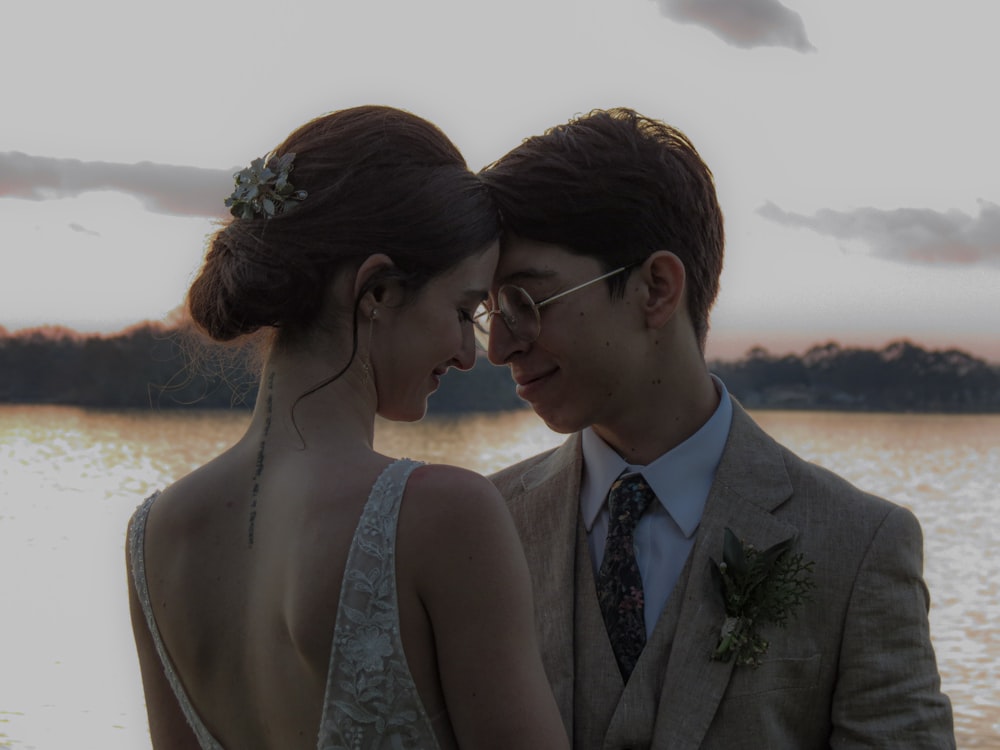 man and woman kissing each other near body of water during daytime