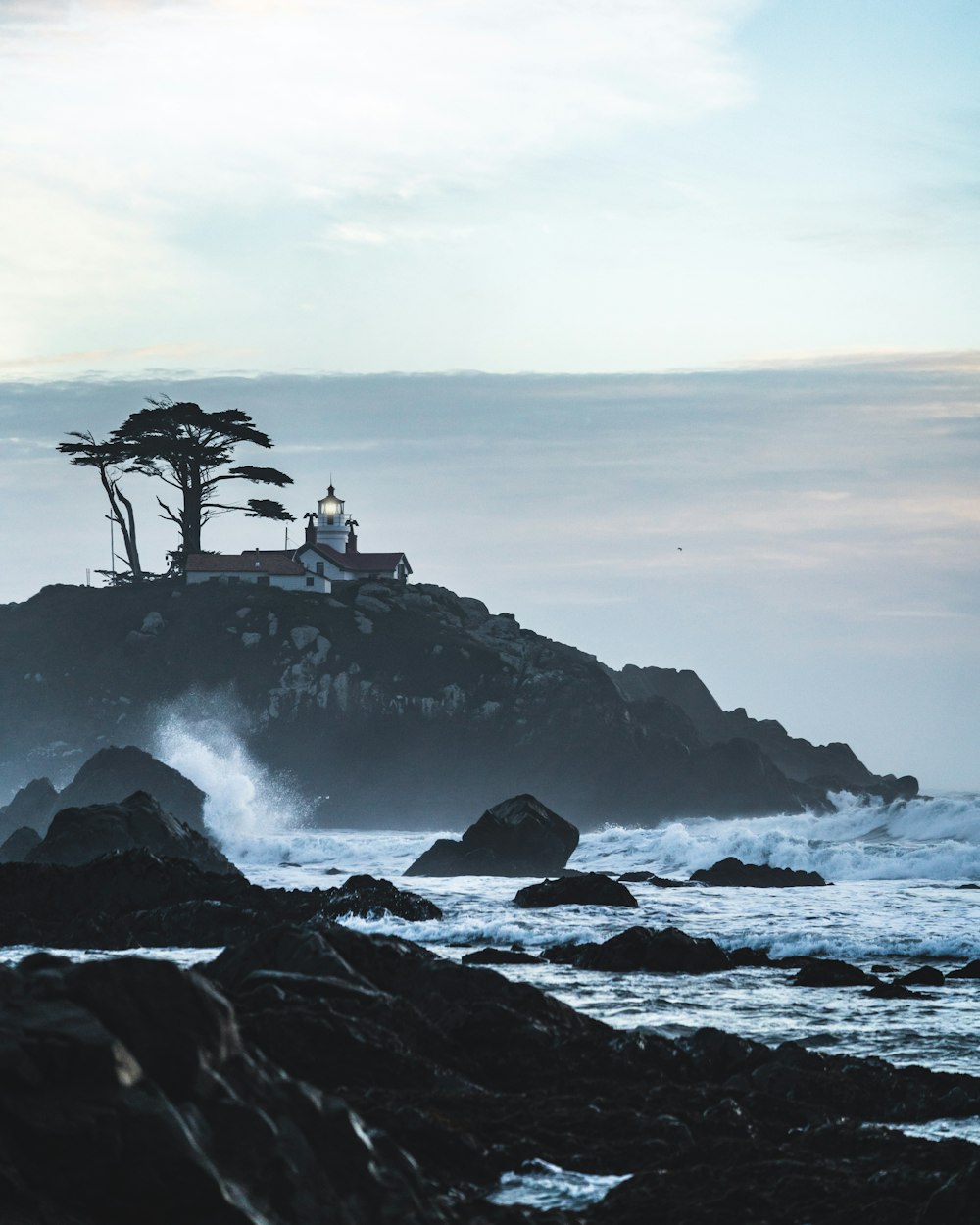 grayscale photo of people on rock formation near sea