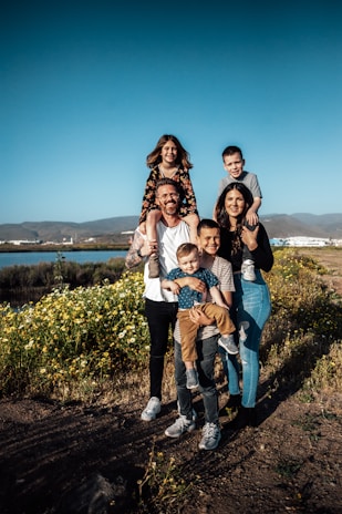 Um casal e quatro crianças posam para fotografia em pé em um campo durante o dia.
