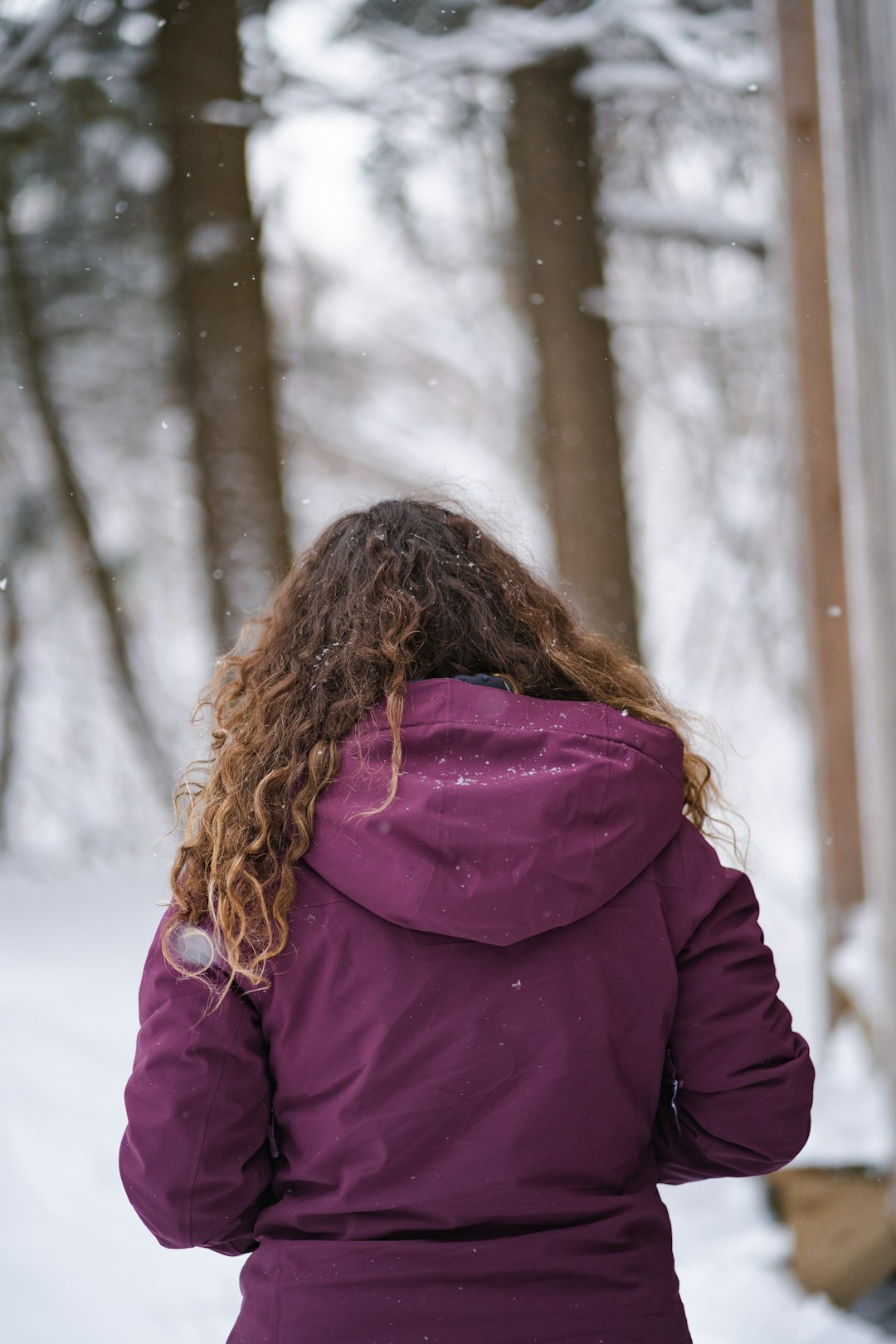 woman in purple coat standing on snow covered ground during daytime