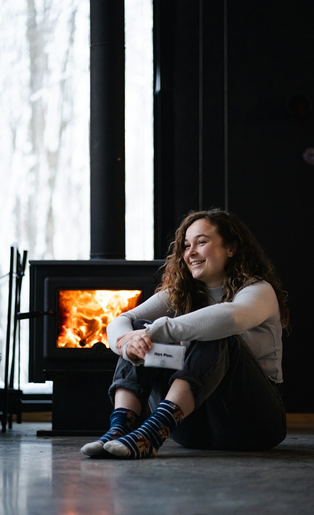 woman in gray shirt sitting on floor near fire