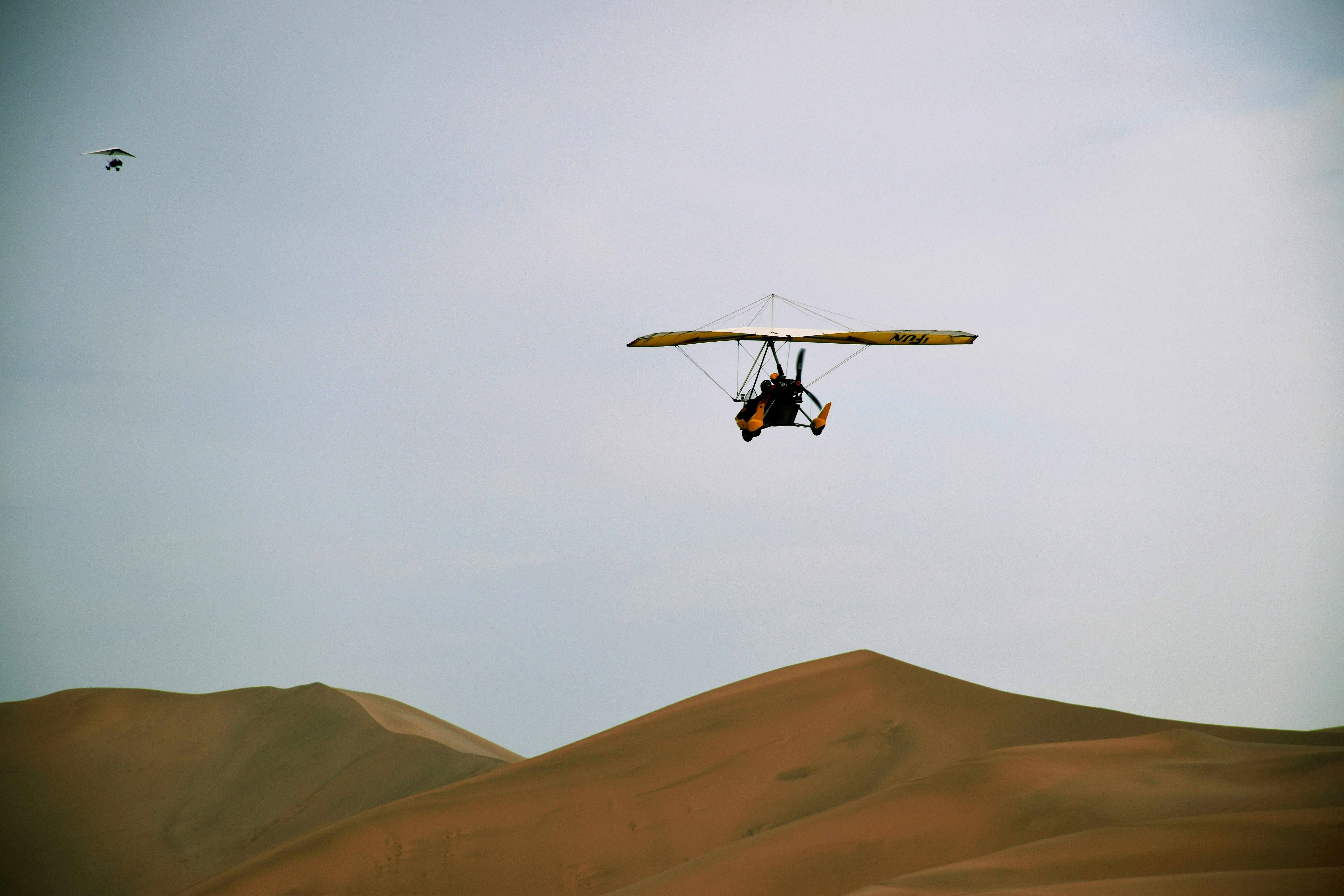 black and white helicopter flying over brown mountain during daytime