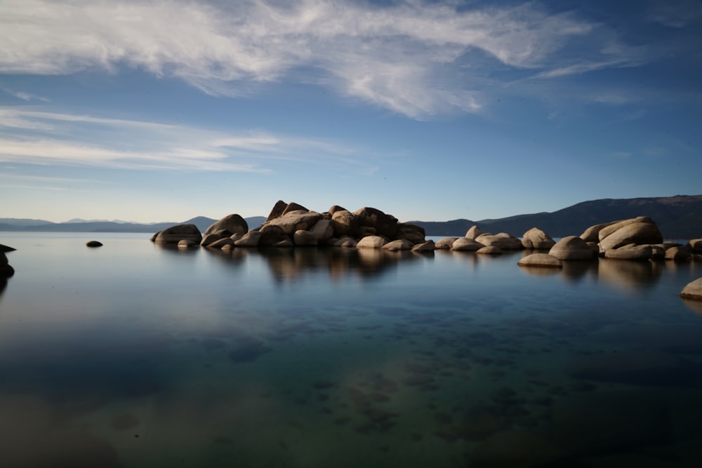 brown rocks on body of water under blue sky during daytime