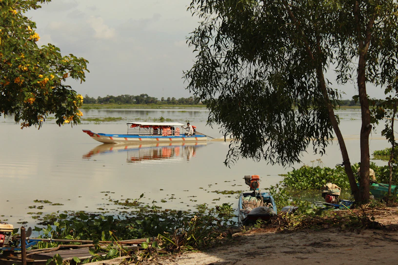 Sleek aqua current electric canal boat gliding smoothly along a serene canal under a clear turquoise sky.