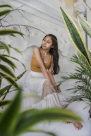 A peaceful woman practicing mindful breathing surrounded by plants and soft light.