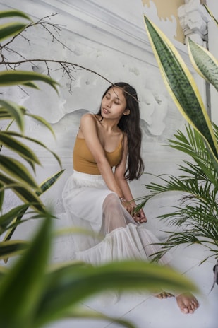 A joyful woman smiling peacefully in a sunlit room filled with plants and spiritual symbols.