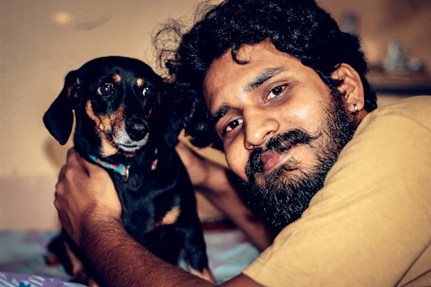 A smiling groomer gently holding a small terrier, both looking content.