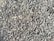 A densely packed pile of small, irregularly shaped gray and brown stones with various textures and shades. The stones appear rough and are closely arranged, suggesting they might be used for construction or landscaping purposes.