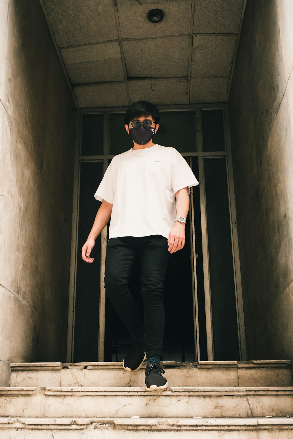 man in white crew neck t-shirt and black pants standing on hallway