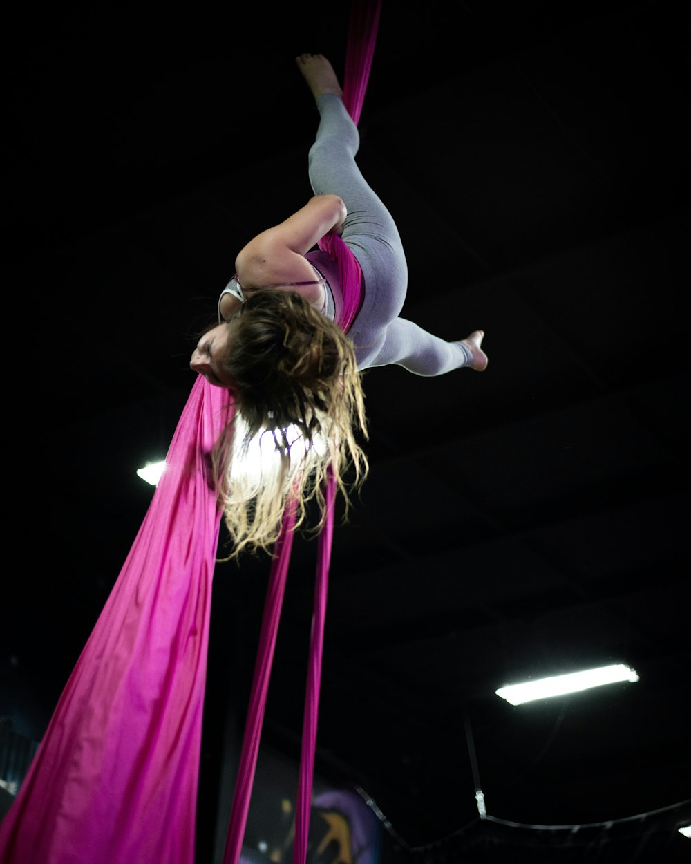 woman in pink tank top and white pants doing yoga